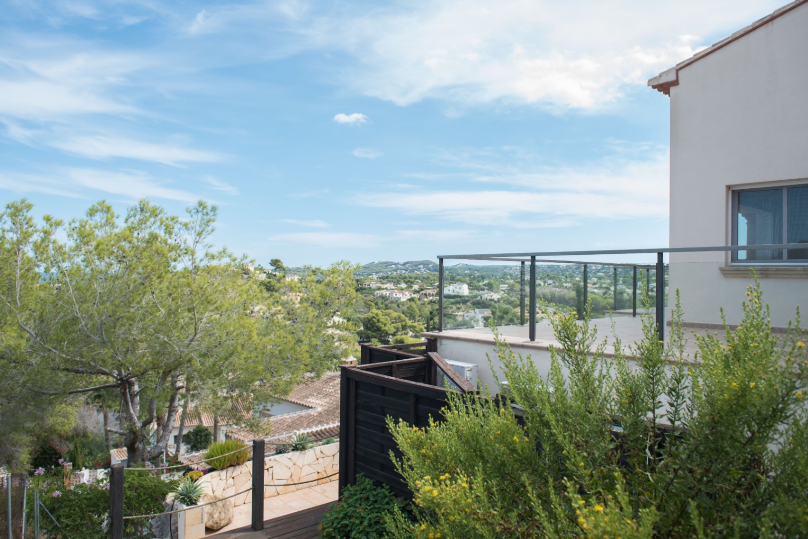 Hochgelegene Terrasse mit Glasgeländer und Panoramablick über das Tal und die umliegende mediterrane Landschaft.