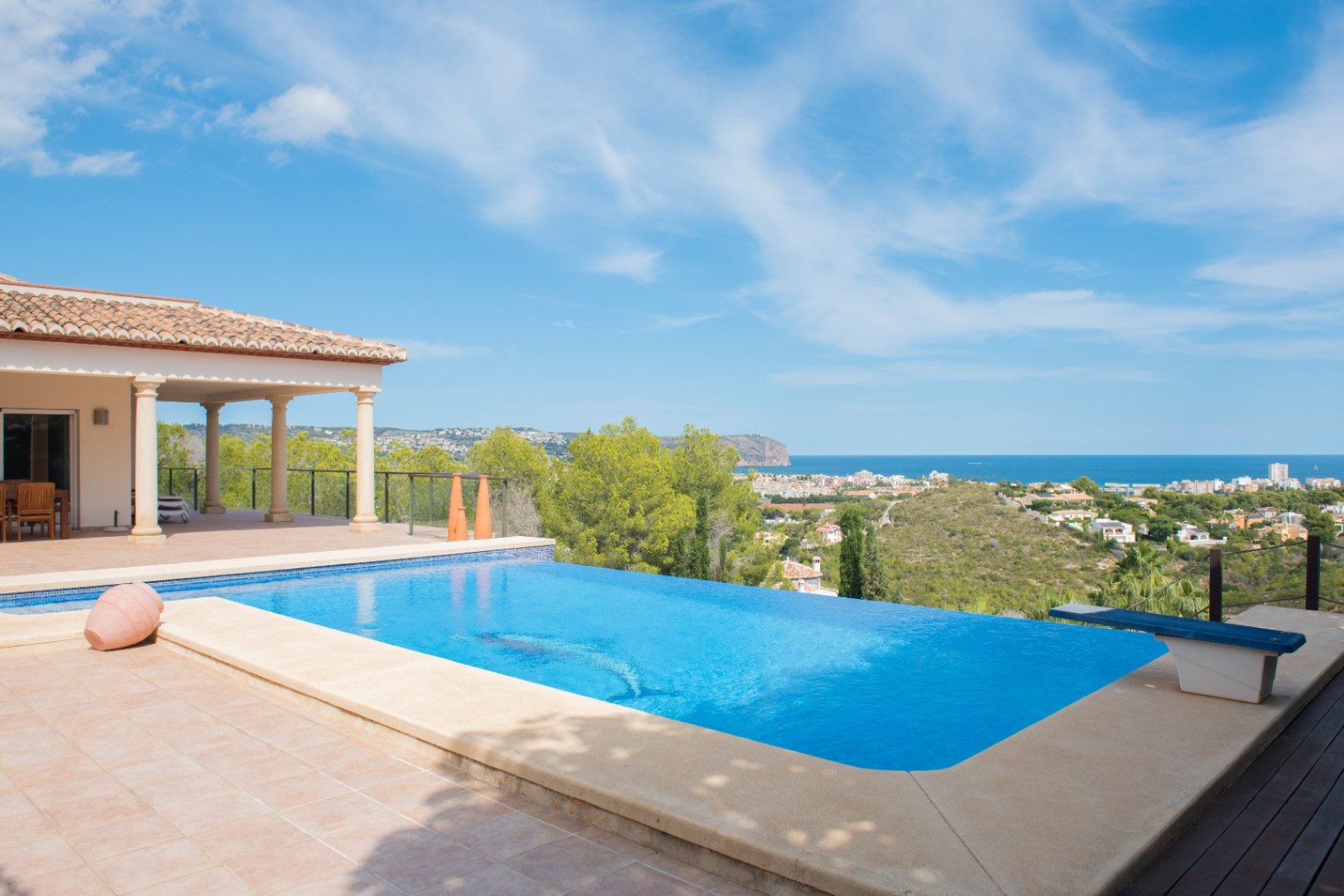 Infinity-Pool mit gefliester Terrasse und Sprungbrett, mit Panoramablick auf die Mittelmeerküste und die umliegenden Pinienwälder.