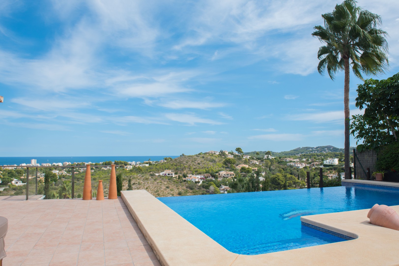 Infinity-Pool mit Steineinfassung und Panoramablick auf das Mittelmeer. Die Terrasse ist mit Terrakottafliesen und dekorativen Elementen gestaltet.