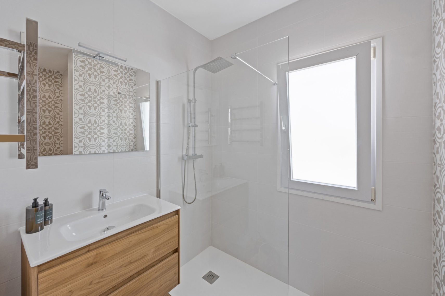 Modernes Bad mit Holz-Waschtisch, integriertem Waschbecken und bodengleicher Dusche mit Glaswand sowie großzügigem Fenster für natürliches Licht.