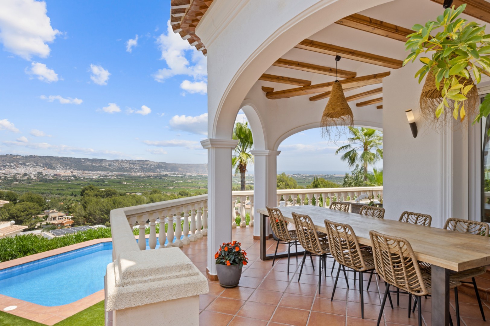 Überdachte Terrasse mit Sichtbalken, großem Esstisch und Panoramablick über das Tal und das Meer oberhalb des privaten Pools.