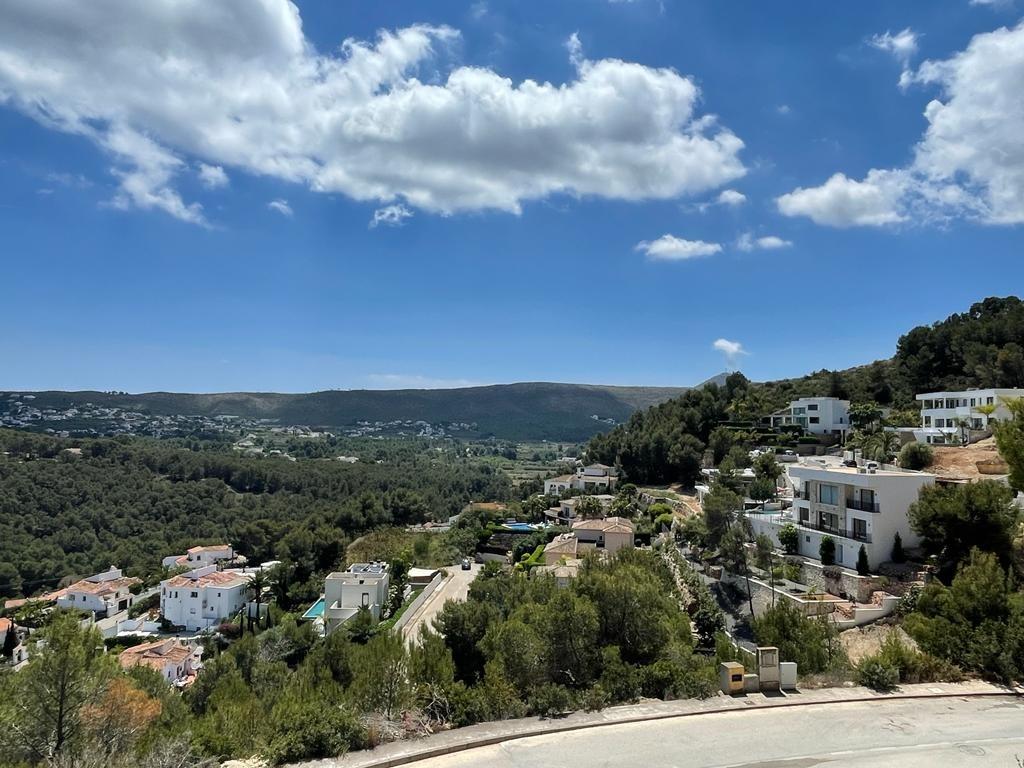 Erhöhter Blick auf ein mediterranes Tal mit weißen Villen, die in dichte Pinienwälder eingebettet sind.