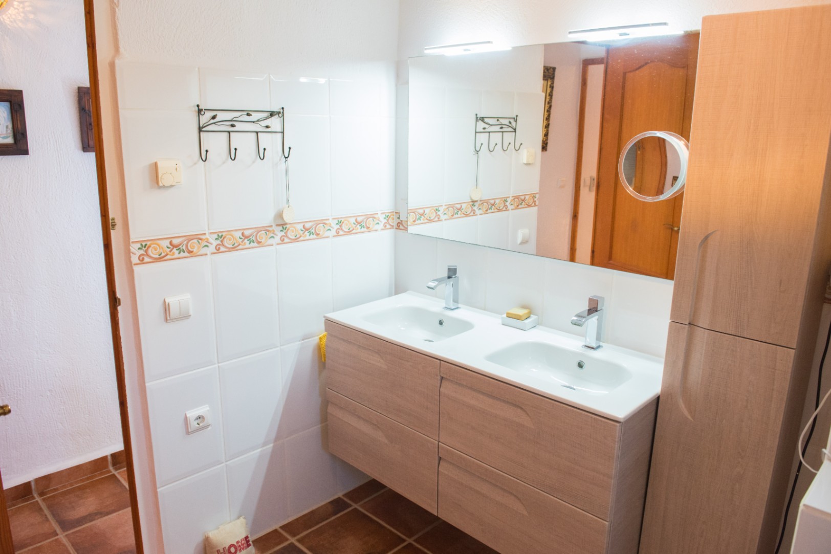Moderner Doppelwaschtisch aus hellem Holz mit integrierten weißen Becken, Chromarmaturen und einem großen Spiegel mit LED-Beleuchtung und Kosmetikspiegel.