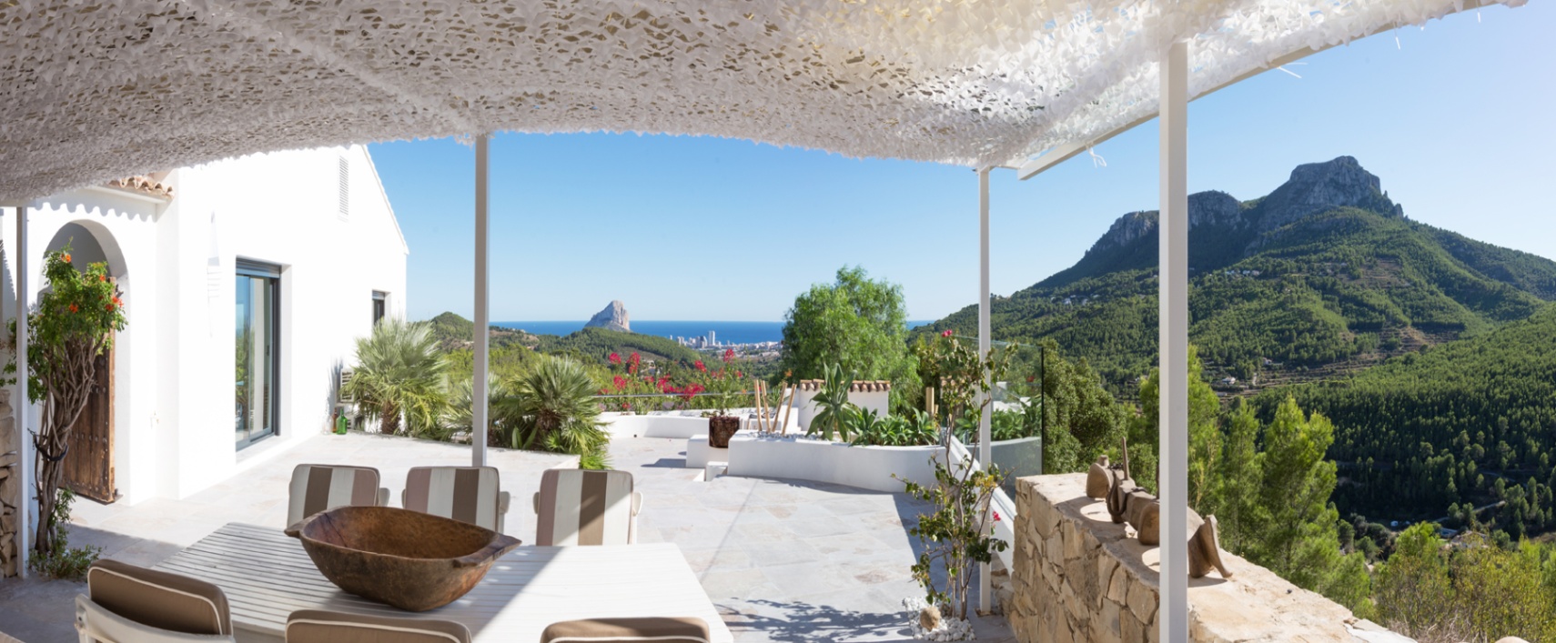 Terrasse mit weißer Pergola und Tarnnetz-Beschattung, Essbereich im Freien mit Blick auf das Mittelmeer, den Peñón de Ifach und die bewaldeten Berge.