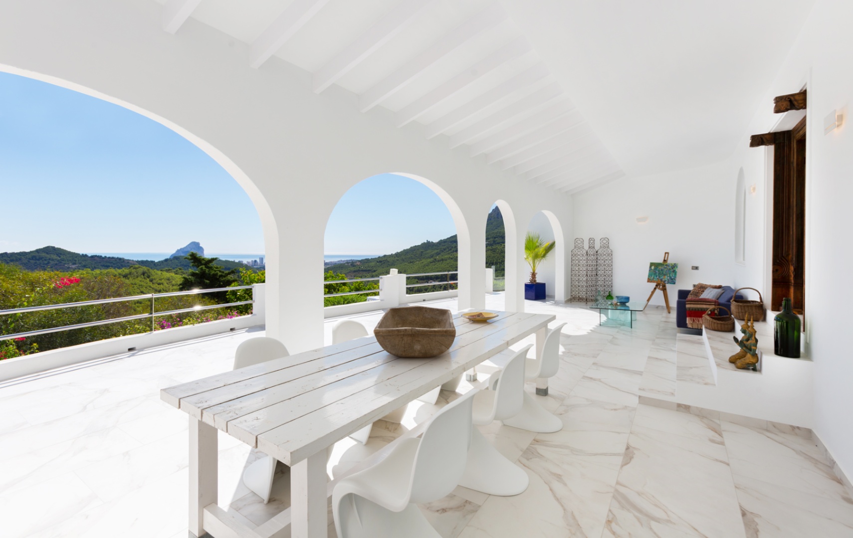 Überdachte Terrasse mit weißen Rundbögen, Marmoreffekt-Boden und Essbereich mit Panoramablick auf die Mittelmeerküste und den Peñón de Ifach.