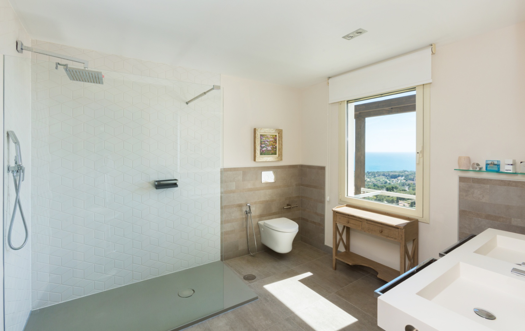 Modernes Badezimmer mit begehbarer Dusche, sechseckigen Fliesen, Doppelwaschtisch und einem großen Fenster mit Panoramablick auf das Meer.