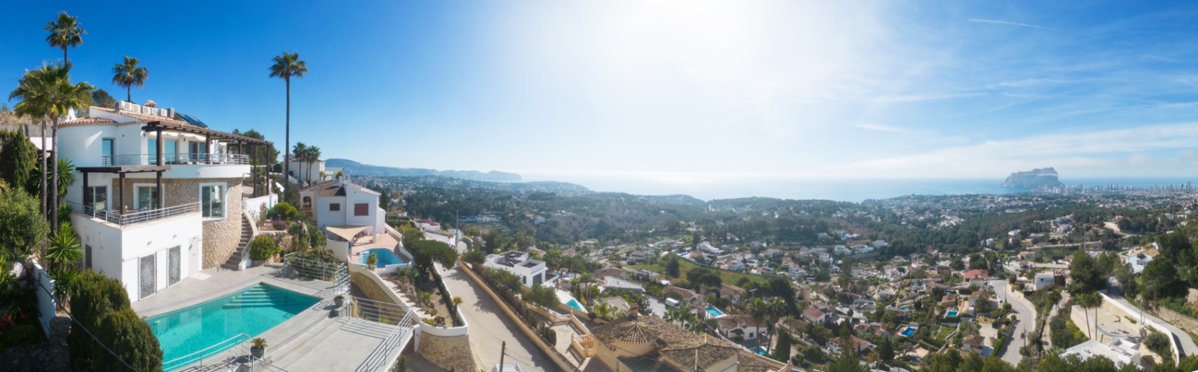 Panoramablick auf eine mediterrane Villa mit privatem Pool, Steinfassaden und weitläufigen Terrassen mit Blick auf die Küste und den Peñón de Ifach.