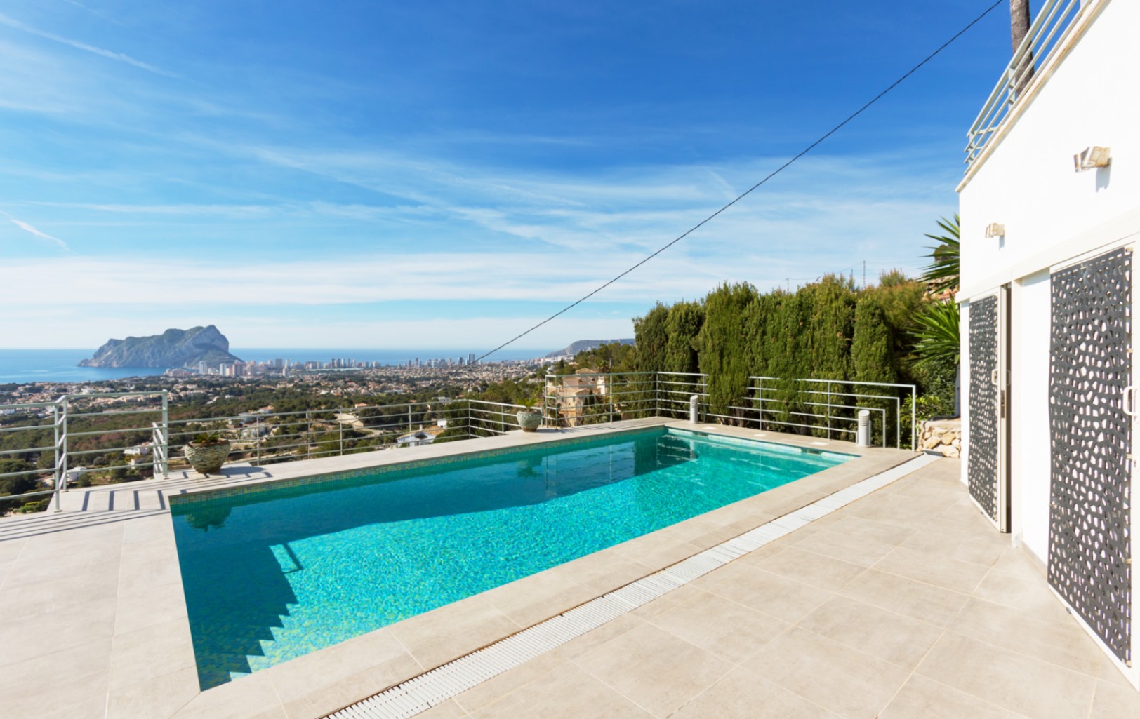 Rechteckiger Außenpool mit gefliester Terrasse und Metallgeländer, der einen Panoramablick auf das Mittelmeer und den Peñón de Ifach in Calpe bietet.
