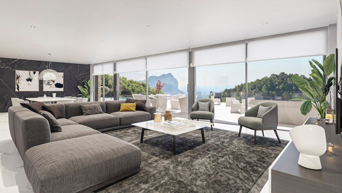 Großzügiger Wohnbereich mit grauem Ecksofa, Marmortisch und bodentiefen Fenstern mit Panoramablick auf den Peñón de Ifach und das Mittelmeer.
