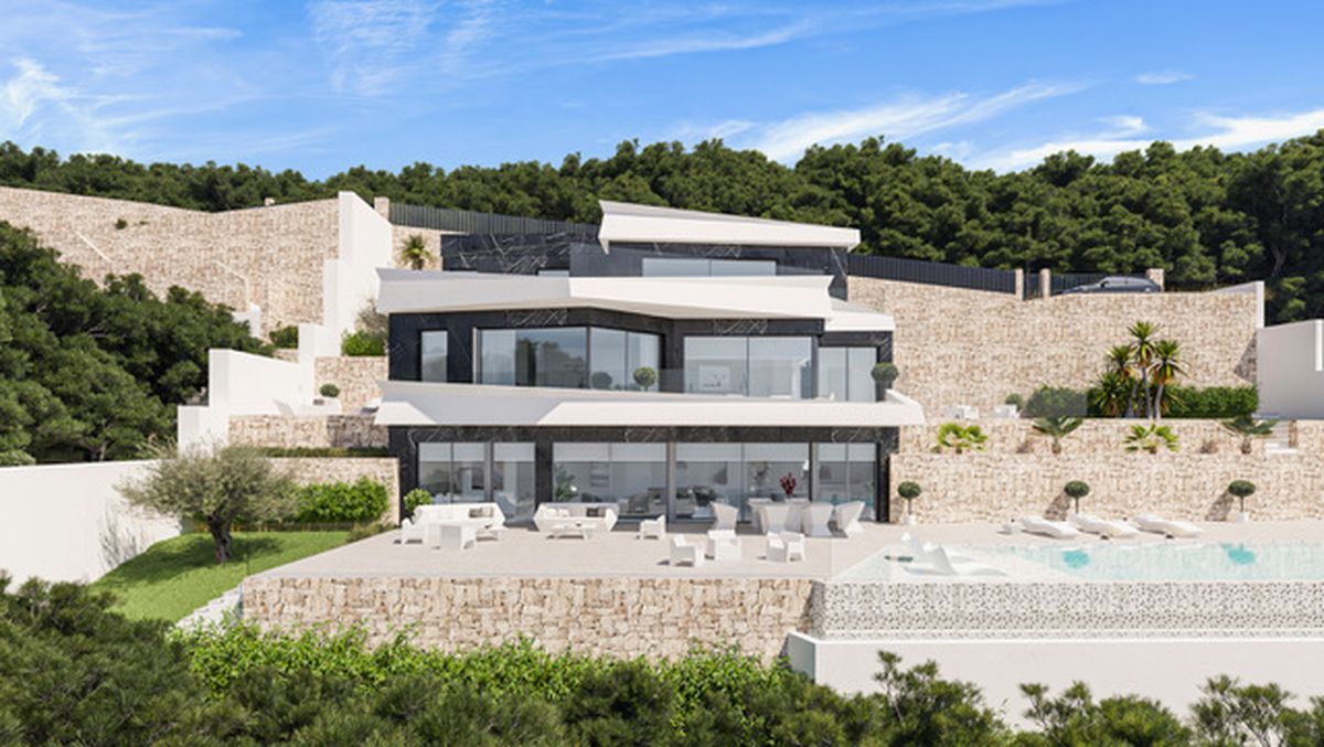 Moderne, mehrstöckige Villa mit weißer und dunkler Steinfassade, großen Glasfronten und in den bewaldeten Hang integrierten Natursteinmauern.