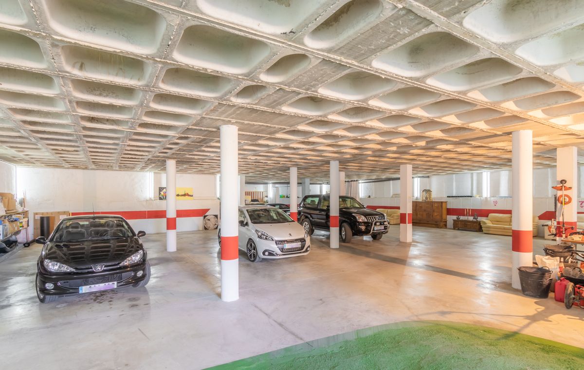 Geräumige Tiefgarage mit markanter Waffelbetondecke, weißen Stützsäulen mit roten Markierungen und ausreichend Platz für mehrere Fahrzeuge auf poliertem Betonboden.