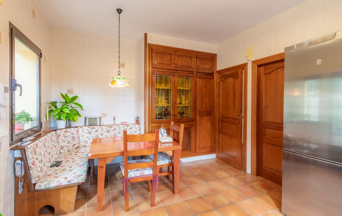 Küchen-Essbereich mit eingebauter Eckbank aus Holz, Terrakottaboden und maßgefertigten Holzschränken mit Bleiglasvitrinen.