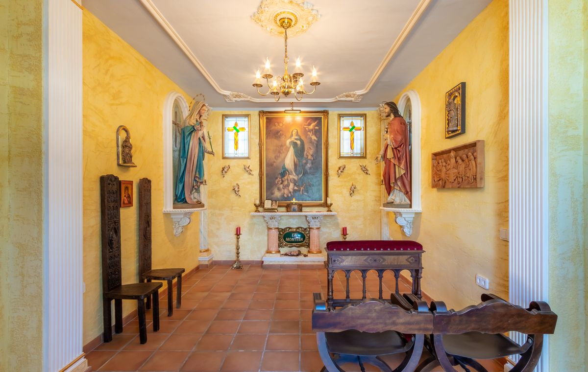 Private Kapelle mit gelb strukturierten Wänden, Terrakottaboden, zentralem Altar mit religiösen Gemälden, Statuennischen und traditionellen Kniebänken aus Holz.