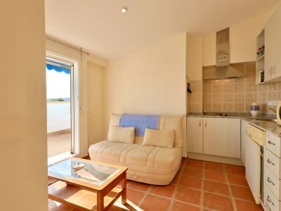 Offener Wohn- und Küchenbereich mit Sofa und Holztisch. Terrakotta-Fliesenboden, ausgestattete Küche mit Dunstabzugshaube, Granit-Arbeitsplatte und Terrassenzugang.