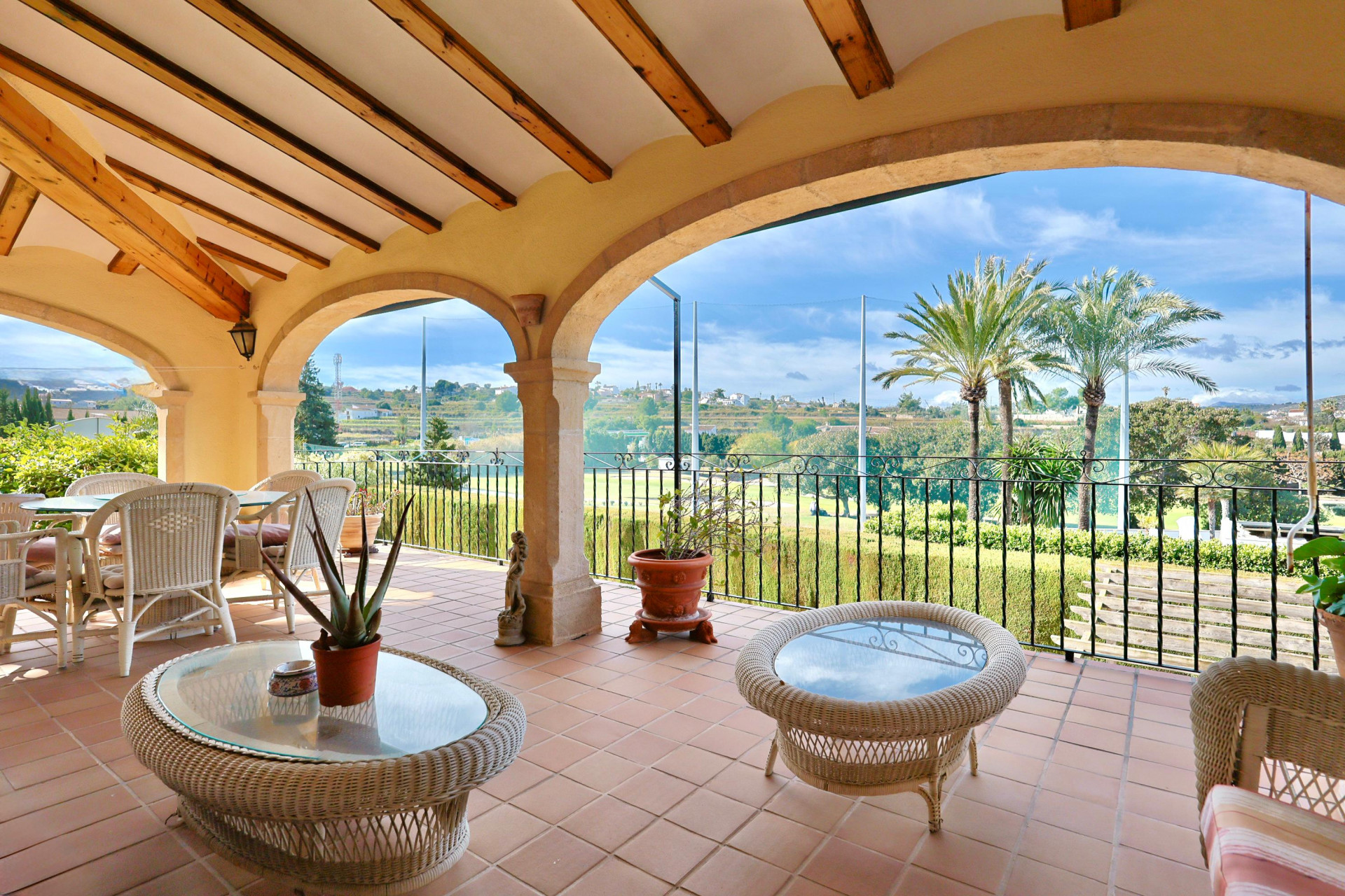 Überdachte Terrasse mit traditionellen Steinbögen, Holzbalkendecke und Terrakottaboden sowie freiem Blick auf den Golfplatz und die umliegende Landschaft.