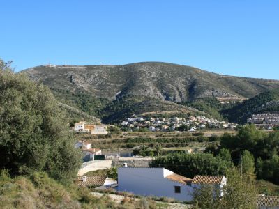 Blick auf die ländliche Landschaft von Benitachell mit Häusern mit Ziegeldächern und Bergkulisse.