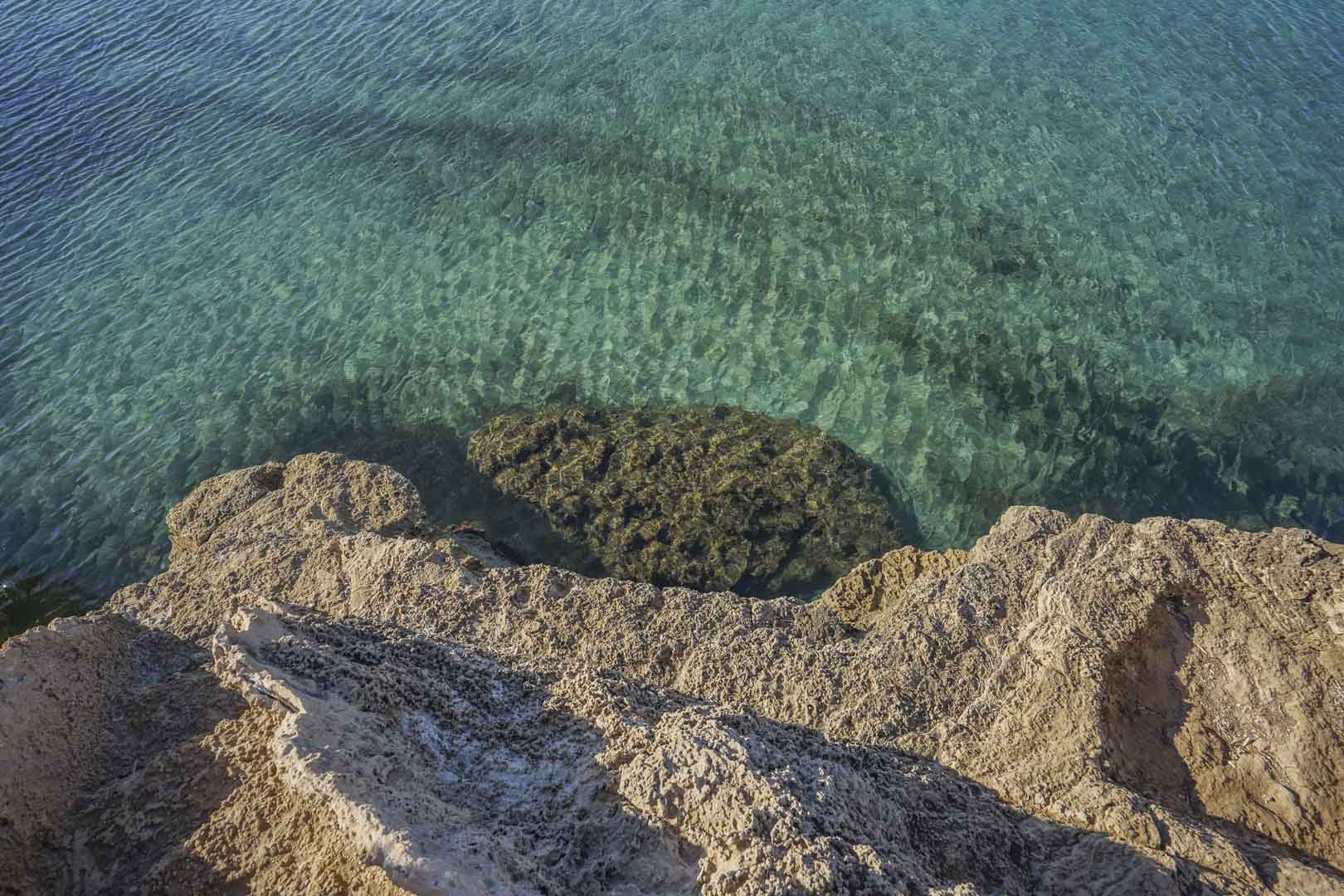 Erhöhte Ansicht des kristallklaren, türkisfarbenen Wassers und der natürlichen Kalksteinfelsen in der Umgebung der Bucht von Granadella in Jávea.