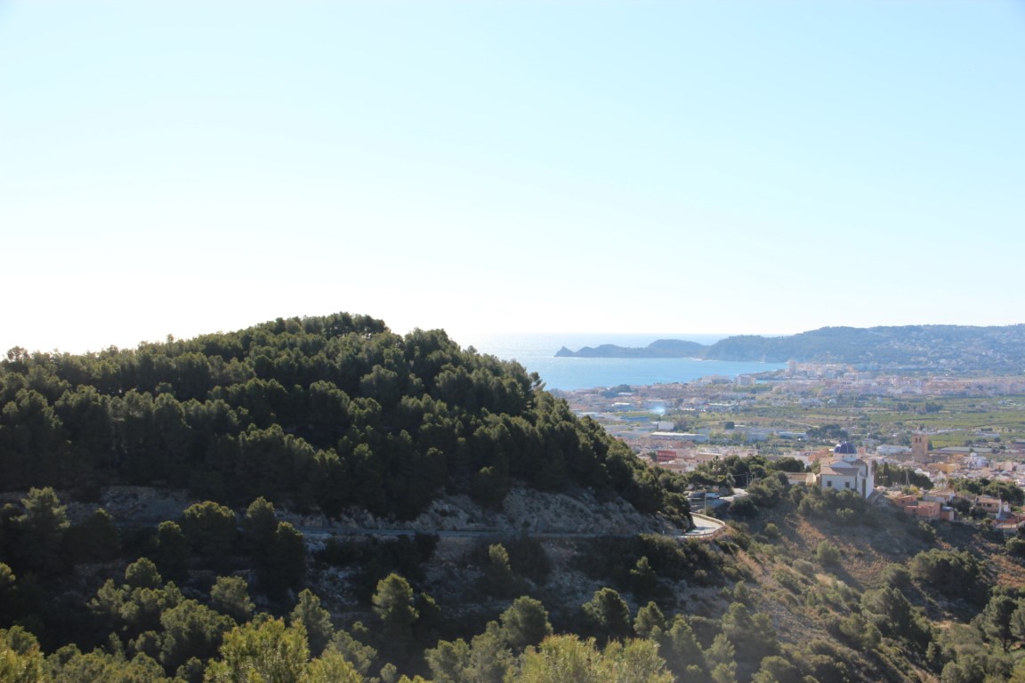 Erhöhter Panoramablick über das Tal von Jávea, die Mittelmeerküste und das historische Stadtzentrum mit seiner markanten blauen Kirchenkuppel.