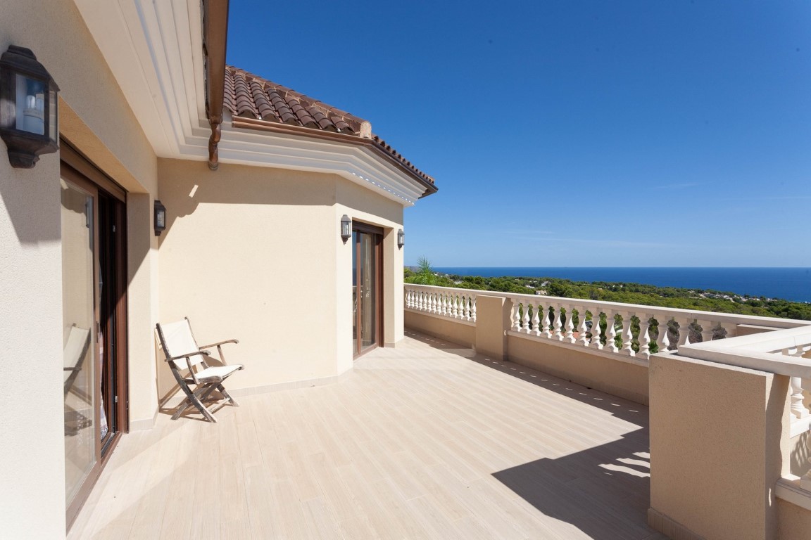 Großer Balkon im Obergeschoss mit klassischer Balustrade, hellem Fliesenboden und Panoramablick auf das Mittelmeer und die umliegende Landschaft.