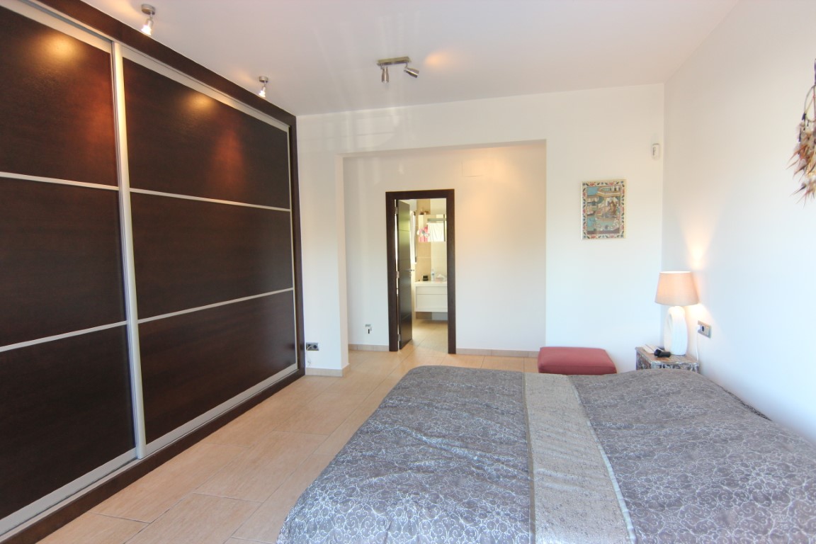 Doppelzimmer mit einem großen Einbauschrank aus dunklem Holz und Schiebetüren. Das Zimmer bietet direkten Zugang zu einem en-suite Badezimmer und verfügt über Fliesenboden.