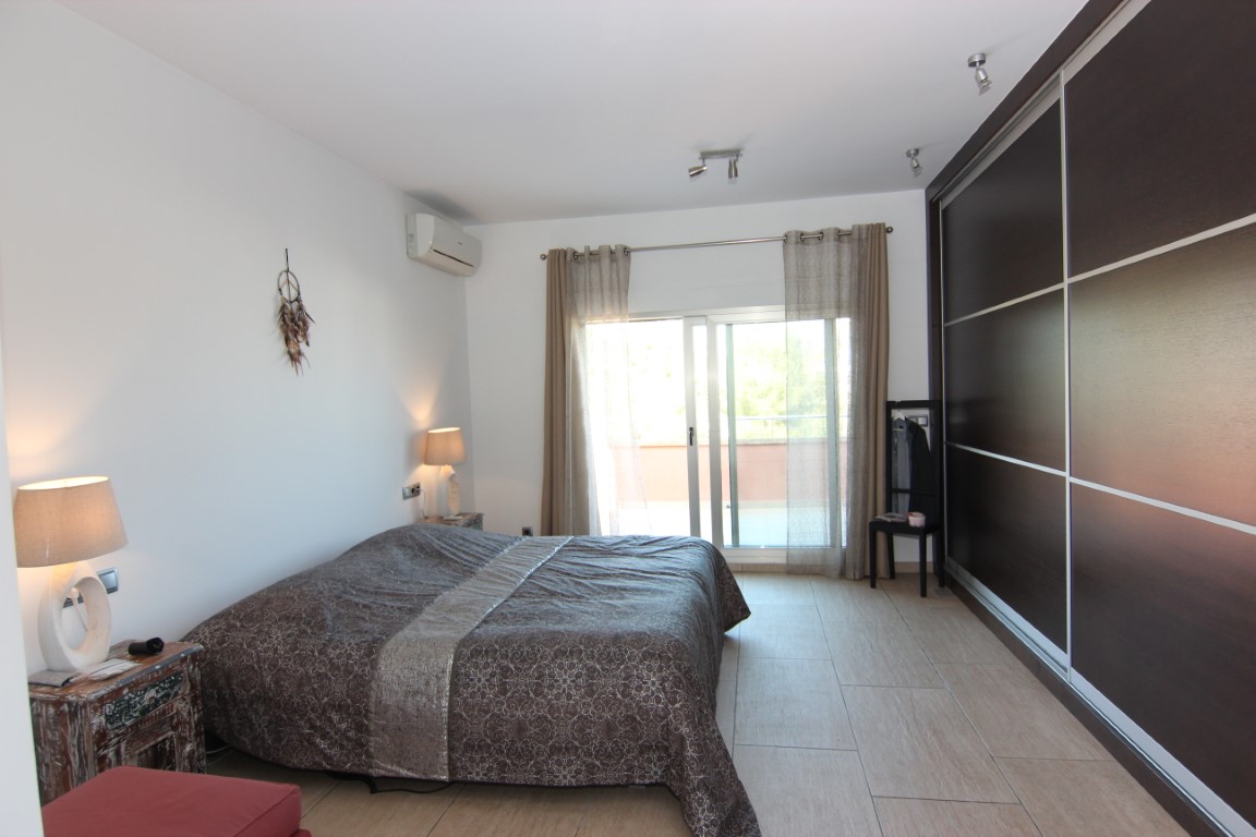 Doppelzimmer mit großem dunklem Schiebetürenschrank, direktem Zugang zur Terrasse und hellen, pflegeleichten Fliesenböden.