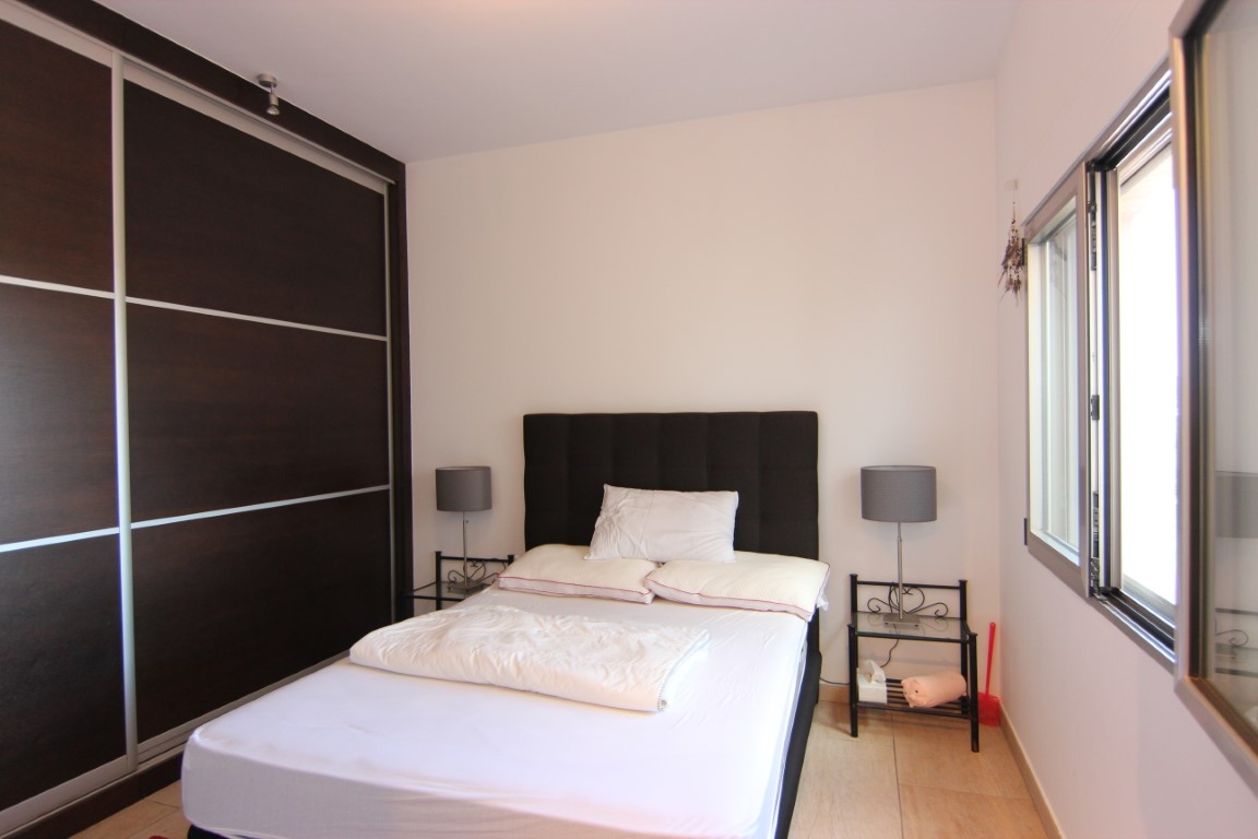 Doppelzimmer mit großem Einbauschrank aus dunklem Holz, minimalistischen Glastischen und natürlichem Lichteinfall durch das Seitenfenster.