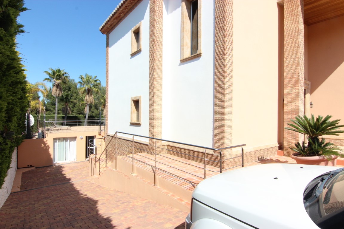 Haupteingang mit barrierefreier Rampe und Edelstahlgeländer. Die Fassade besticht durch dekorative Backsteinsäulen und Fensterumrandungen aus Naturstein.
