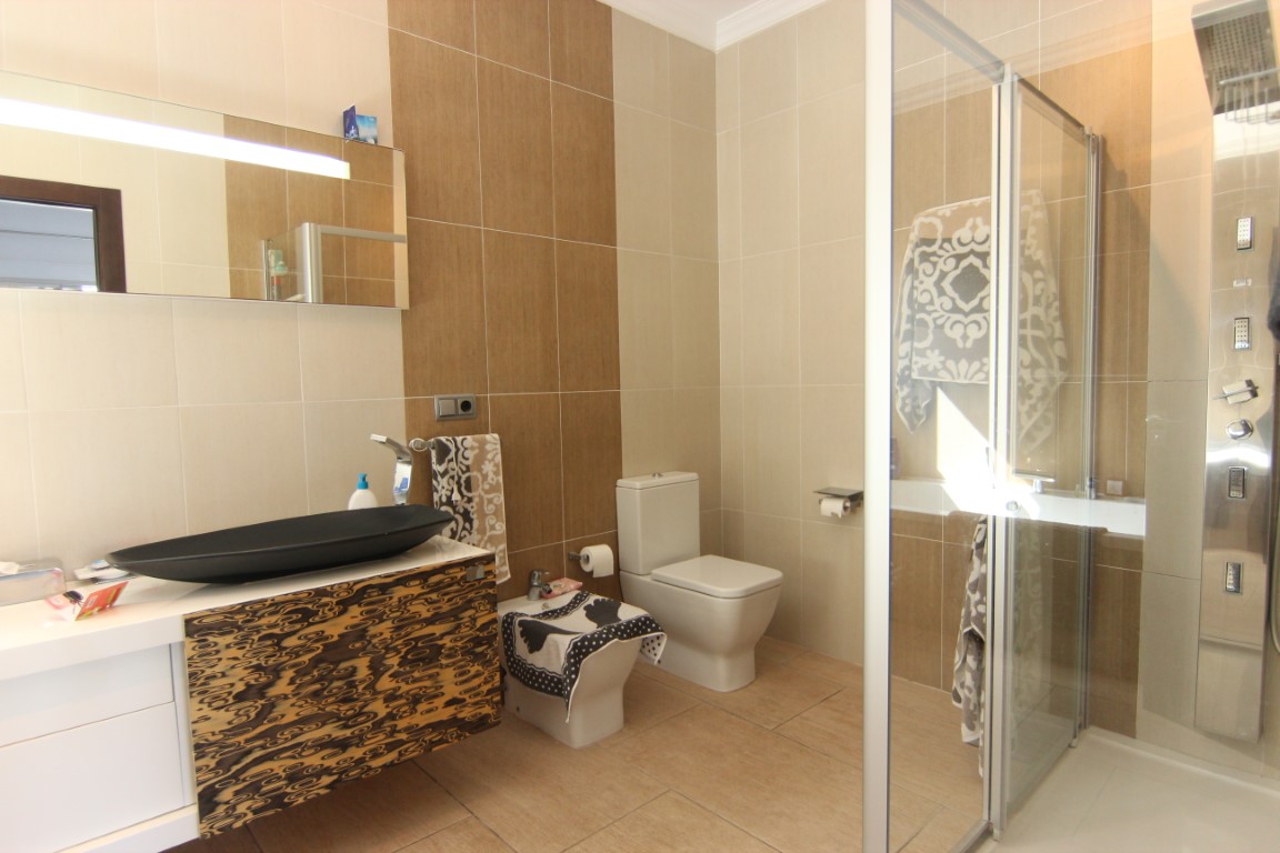 Modernes Badezimmer mit schwarzem Aufsatzwaschbecken, strukturiertem Unterschrank und Dusche mit Hydromassage-Paneel und Glaskabine.