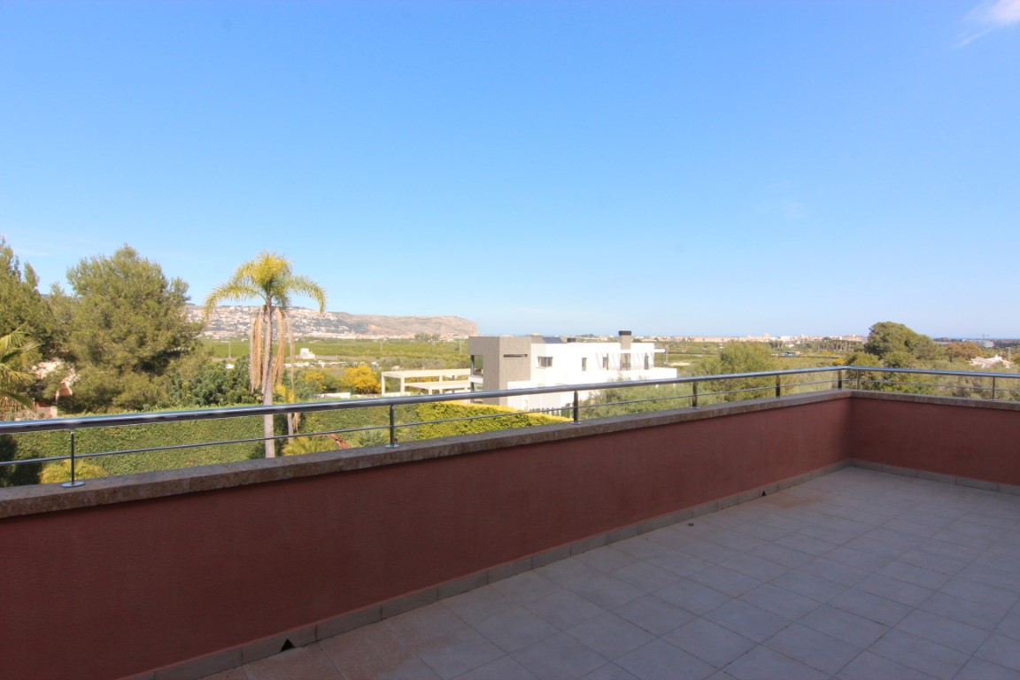 Obergeschoss-Terrasse mit Edelstahlgeländer und Steinabdeckung, die einen weiten Panoramablick über das Tal und die Berge bietet.