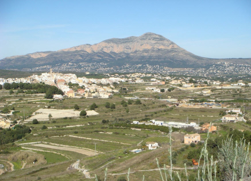 Panoramablick auf das terrassierte Grundstück in Benitachell mit dem Montgó-Massiv im Hintergrund und Blick auf den historischen Ortskern.