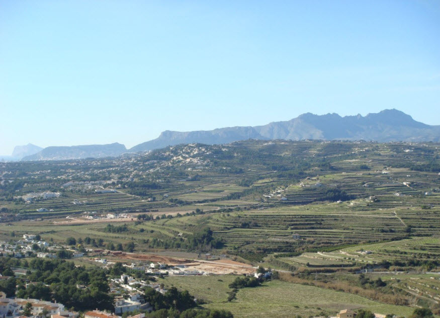 Panoramablick auf die landwirtschaftlichen Terrassen und die Bergketten von Benitachell, der die natürliche Umgebung des Grundstücks zeigt.