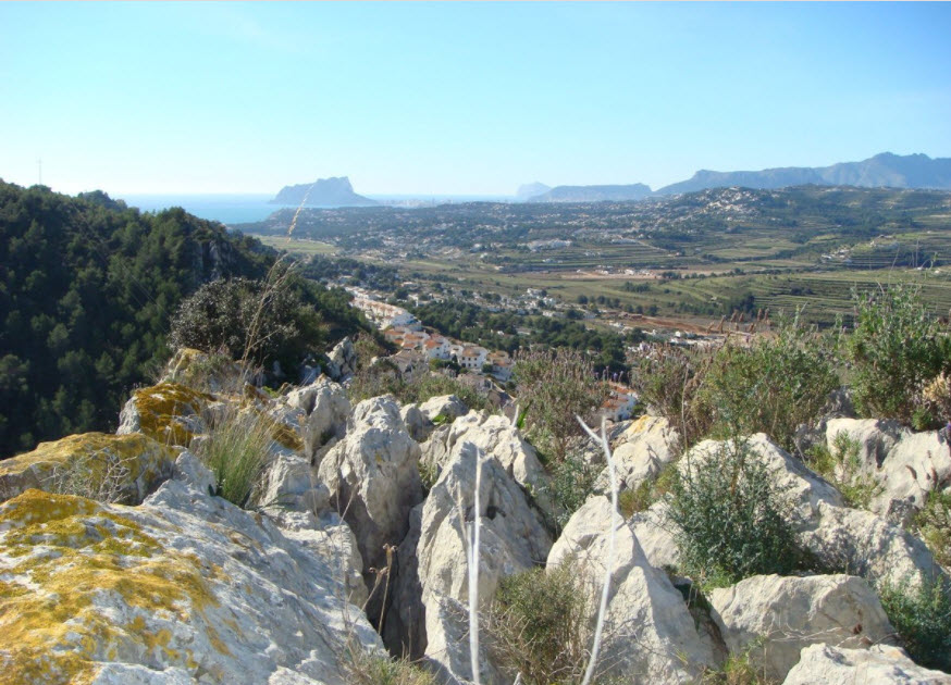 Panoramablick vom erhöhten Grundstück auf den Peñón de Ifach und das Mittelmeer, mit natürlichen Felsformationen und einheimischer Vegetation.