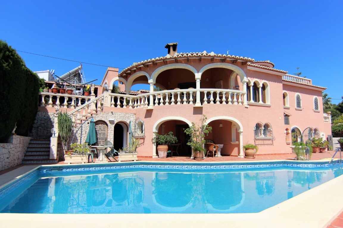 Außenansicht der Villa mit großem Pool und zweistöckigen Rundbogenterrassen, die den mediterranen Baustil mit Balustraden betonen.
