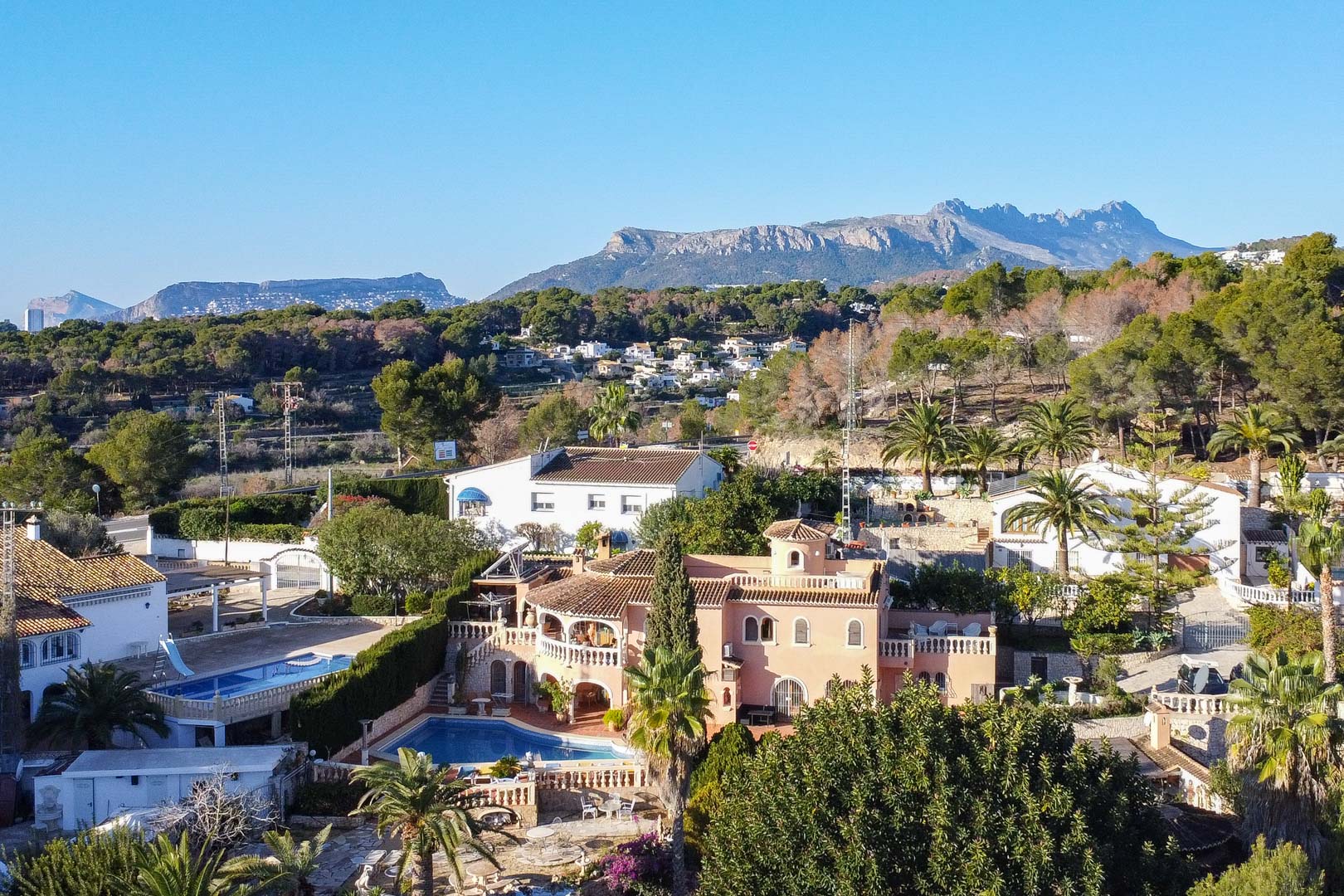 Luftaufnahme der mediterranen Villa mit privatem Pool und großzügigen Terrassen, eingebettet in eine grüne Landschaft mit Blick auf die Berge.
