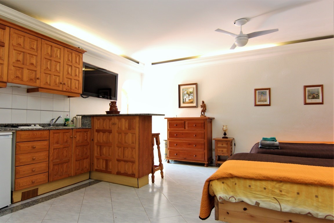 Studio-Apartment mit integrierter Holzküche, Granitarbeitsplatte und zwei Einzelbetten. Ausgestattet mit Deckenventilator, Fliesenboden und indirekter Deckenbeleuchtung.