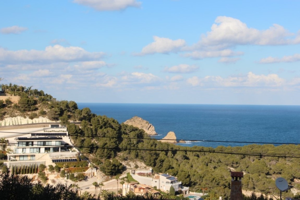 Panoramablick vom Grundstück auf das Mittelmeer und die Insel Portichol, mit modernen Villen inmitten der bewaldeten Hügel von Jávea.