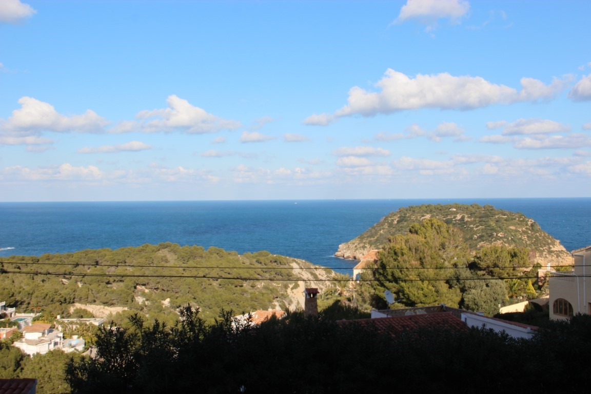 Panoramablick vom Grundstück auf das Mittelmeer und die Insel Portichol, umgeben von grünen Hügeln und traditionellen Hausdächern unter blauem Himmel.