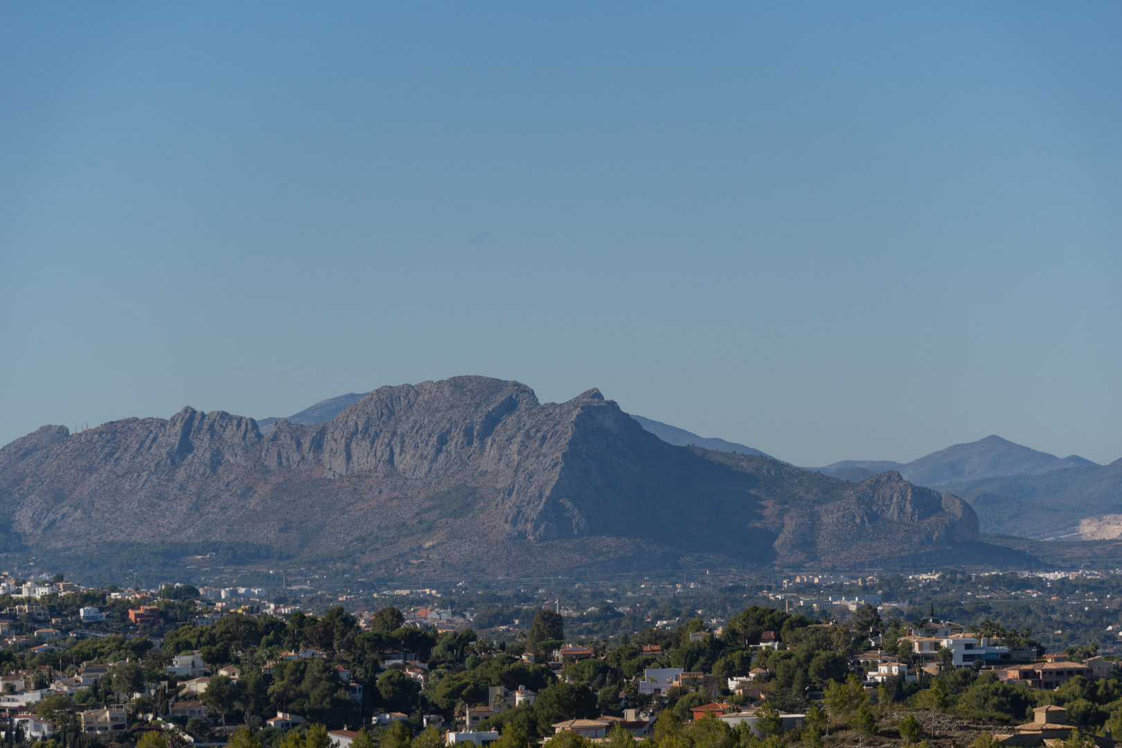 Panoramablick auf das Montgó-Massiv und die umliegende Wohnlandschaft von Denia unter strahlend blauem Himmel.