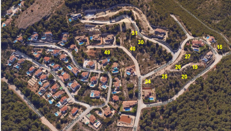 Luftaufnahme der Erschließung in Jávea mit nummerierten Baugrundstücken, umgeben von Pinienwäldern, asphaltierten Straßen und bestehenden Villen.