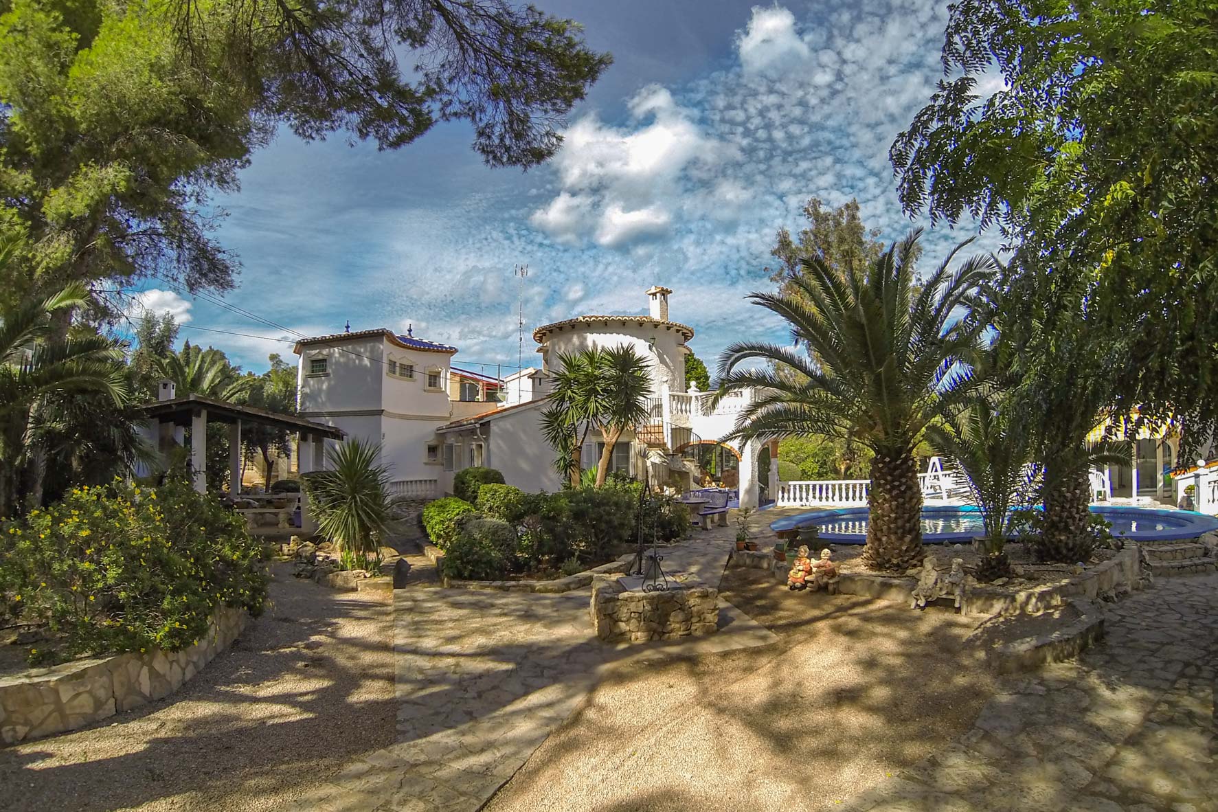 Ansicht des gewachsenen Gartens mit rundem Pool und Haupthaus im mediterranen Stil.