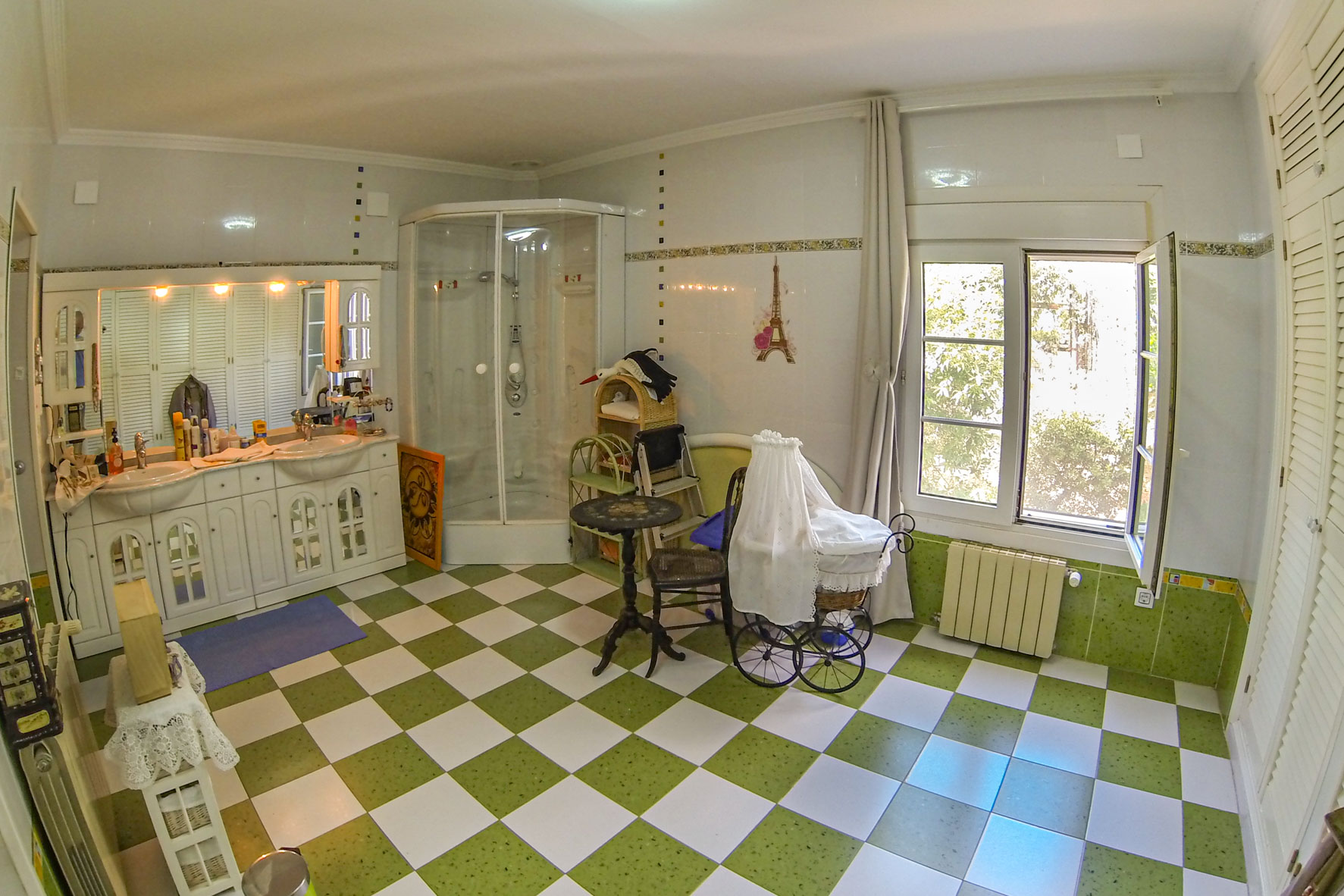 Badezimmer mit grün-weißem Schachbrettfliesenboden, Eckdusche und Doppelwaschtisch mit weißen Schränken.