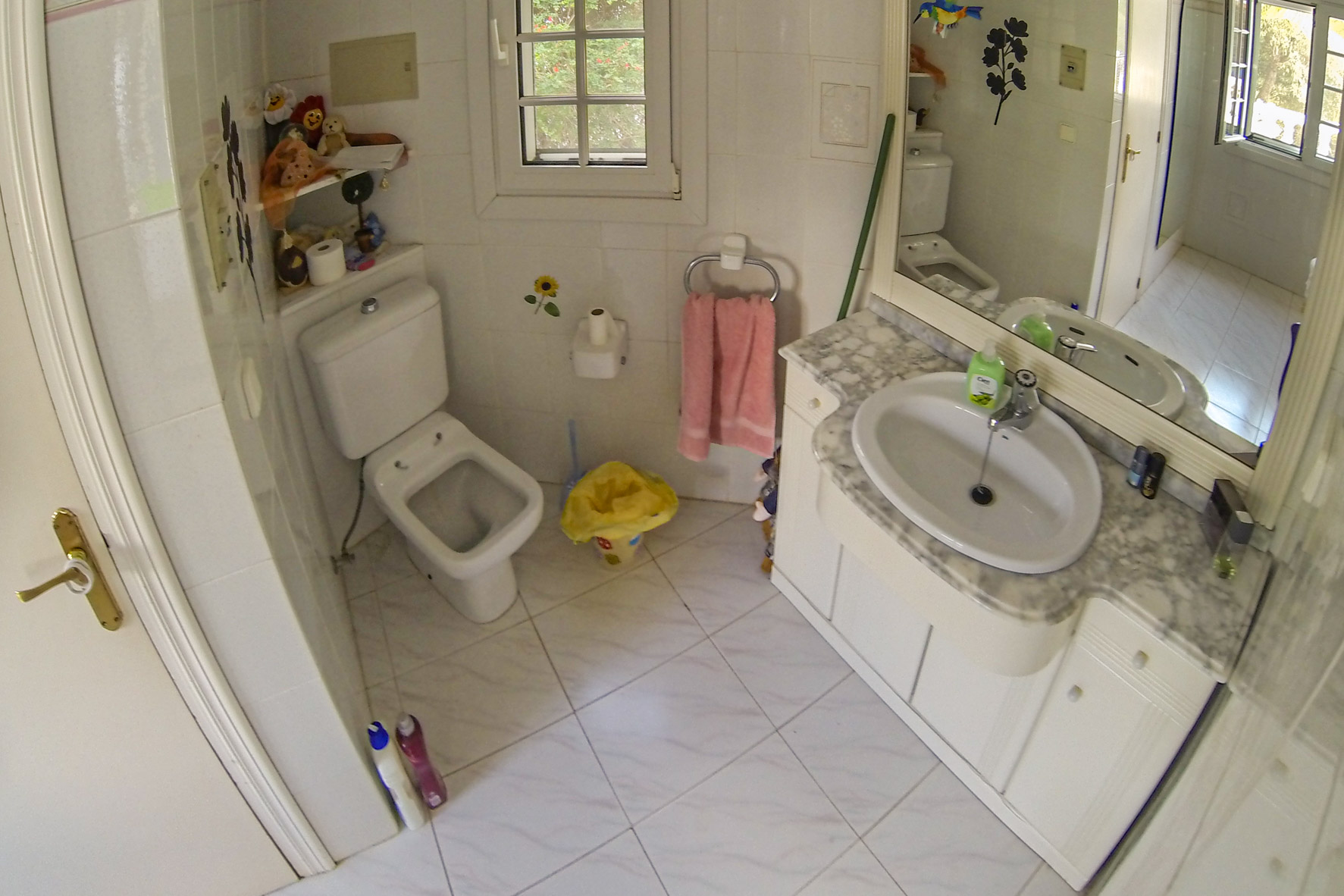 Badezimmer mit Marmorwaschtisch, Toilette und weißen Fliesen.