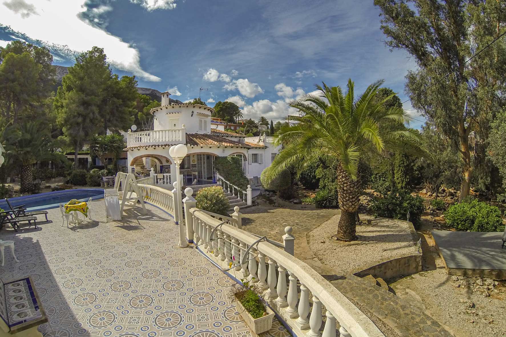 Blick auf die Terrasse mit gemusterten Fliesen, Balustradengeländer und Poolbereich der Villa.