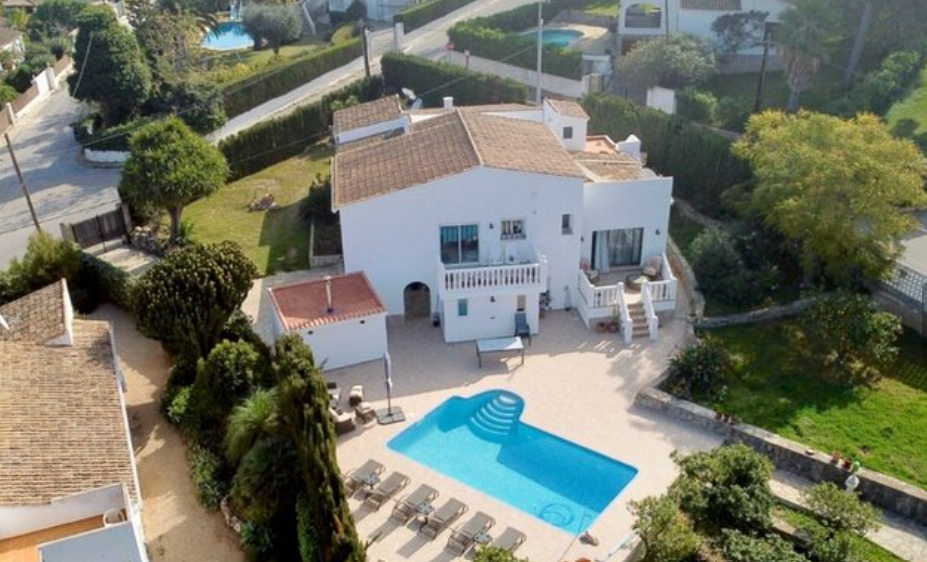 Luftaufnahme der Villa mit privatem Pool, großzügiger Sonnenterrasse mit Liegen und einem gepflegten Garten, der das traditionelle weiße Gebäude umgibt.