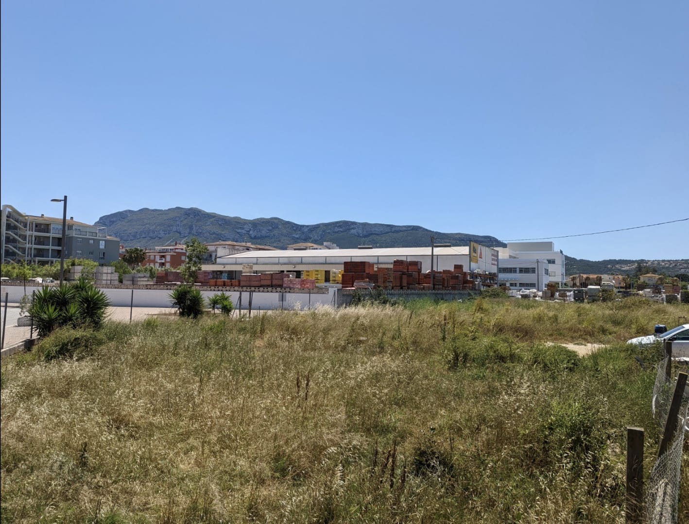 Ebenes Grundstück mit natürlicher Vegetation und freiem Blick auf den Montgó, in direkter Nachbarschaft zu Gewerbe- und Wohngebieten gelegen.