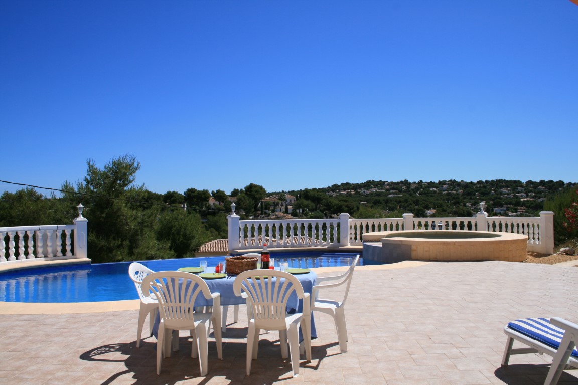 Großzügige Außenterrasse mit geschwungenem Pool, integriertem Rund-Whirlpool und Essbereich mit Panoramablick auf die Hügel von Javea.