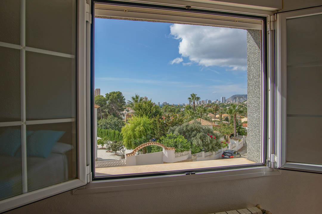 Erhöhter Ausblick aus dem Schlafzimmerfenster auf die umliegende Wohngegend, mediterrane Gärten und die ferne Skyline der Stadt.