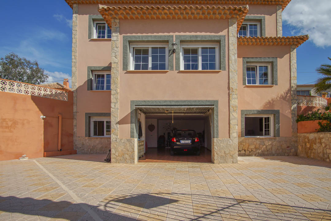 Vorderansicht der Villa mit großzügiger gepflasterter Einfahrt und integrierter Garage. Die dreistöckige Bauweise besticht durch Natursteinakzente und solide Verarbeitung.