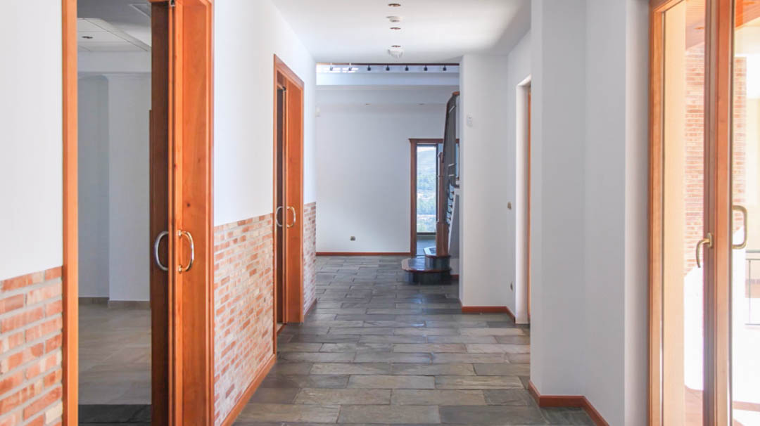 Heller Flur mit Naturschieferboden, dekorativer Backstein-Wandverkleidung und hochwertigen Holzschiebetüren, die zu den verschiedenen Wohnräumen führen.