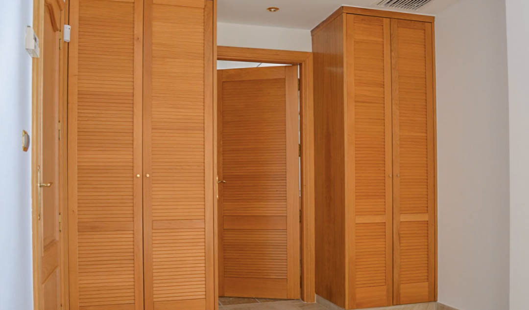 Hochwertige Einbauschränke aus Holz mit Lamellentüren, passend zur Innentür gestaltet, in einem hellen Flur mit Deckeneinbaustrahlern.